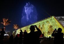 واجهة المتحف المصري الكبير مضاءة ليلا مع عرض درونز على شكل قناع توت عنخ آمون
