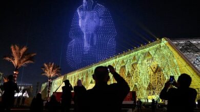 واجهة المتحف المصري الكبير مضاءة ليلا مع عرض درونز على شكل قناع توت عنخ آمون