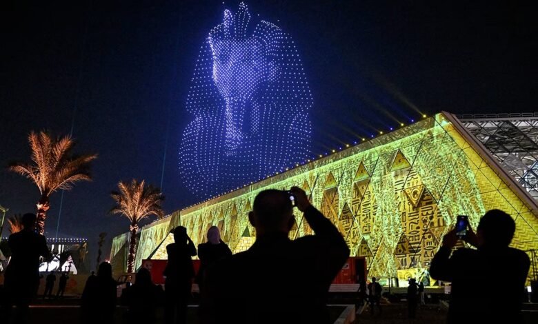 واجهة المتحف المصري الكبير مضاءة ليلا مع عرض درونز على شكل قناع توت عنخ آمون